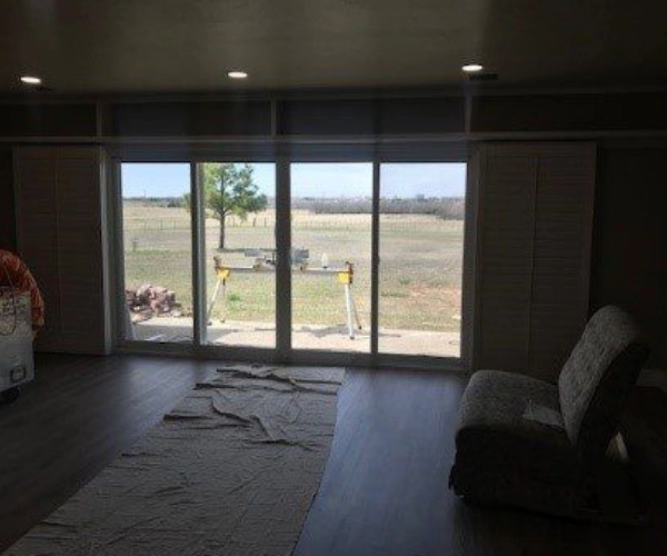 A large window of a house with a large field on the outside